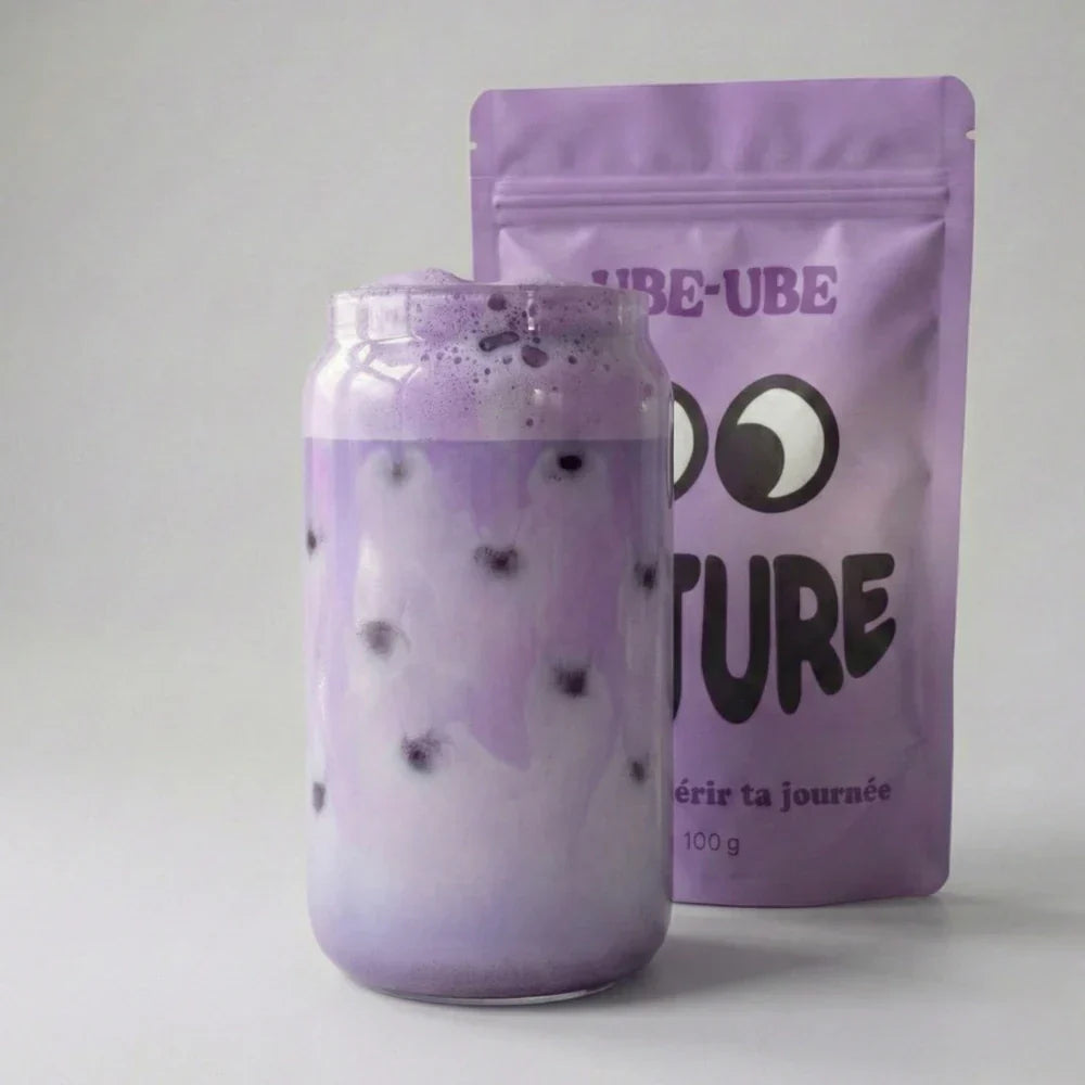 Ube latte violet maison dans un verre avec le sachet de poudre d'ube Ube-Ube en arrière-plan