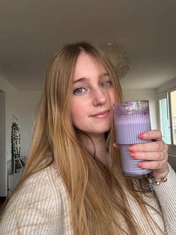 La co-fondatrice d'Ube-Ube dégustant un ube latte à la poudre d'ube dans un verre cannelé, chez elle