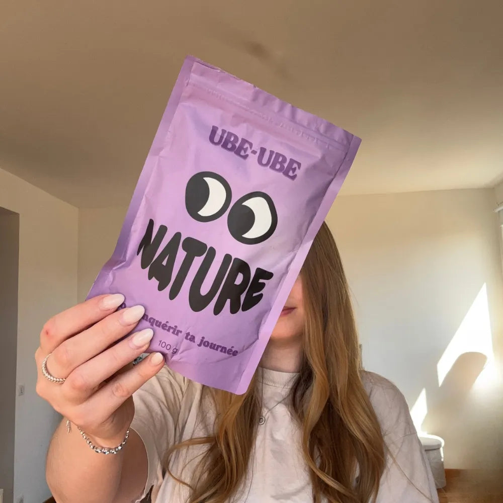 La co-fondatrice d'Ube-Ube tenant le sachet de poudre d'ube Nature 100g, packaging violet refermable
