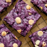 Brownies à la poudre d'ube violet intense et chips de chocolat blanc, texture fudgy et gourmande sur grille de refroidissement
