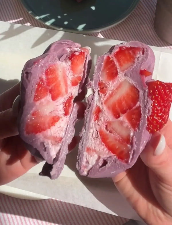 Glace maison à la poudre d'ube et fraises fraîches coupée en deux, crème violette et fruits rouges incrustés