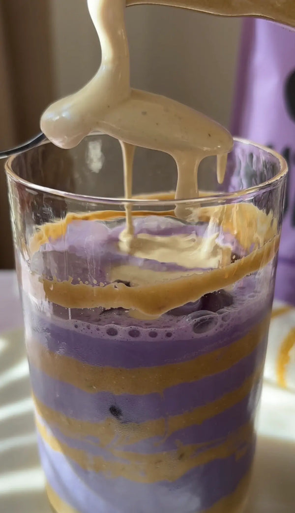 Recette ube latte pistache : versement de crème de pistache dorée sur la préparation à la poudre d'ube, strates violettes et dorées